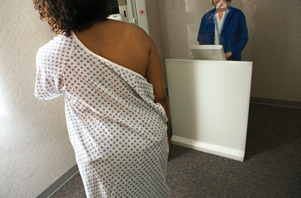 Woman in hospital gown walks to screening room