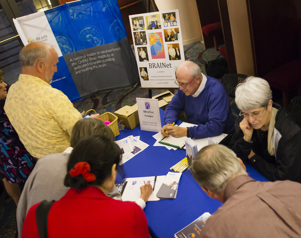 BRAINet volunteers sit at a table helping patrons learn about neuroscience.