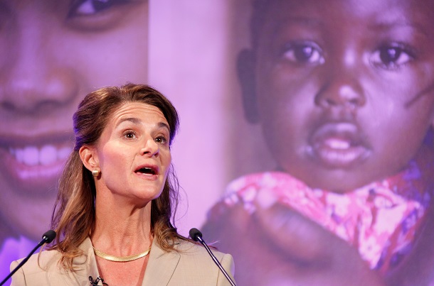 Melinda Gates in front of a screen showing children