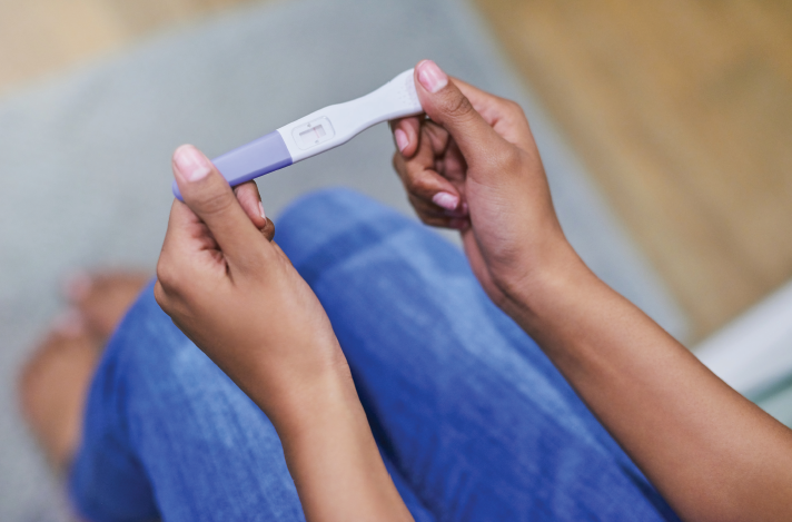 Woman holds pregnancy test above knees