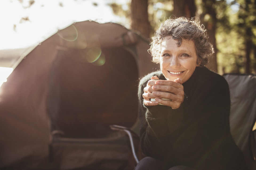 Woman in front of tent holding mug