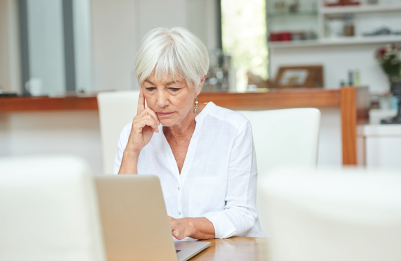 woman sits at computer looking thoughtful