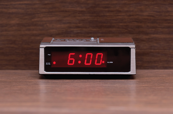 Digital alarm clock reading 6:00 a.m.