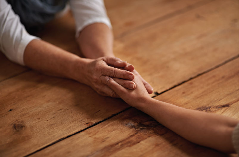 two people hold hands across a wooden table