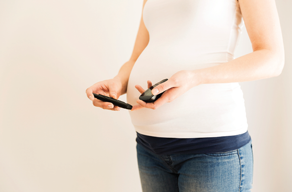 pregnant woman holds blood sugar meter