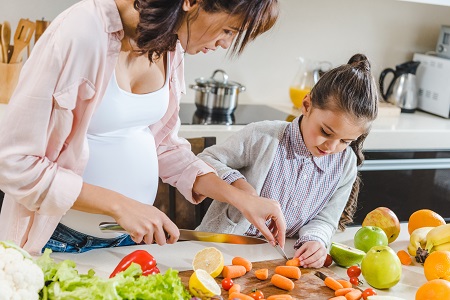 Pregnant mom and daughter cooking