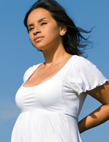 An expectant mother stands in the breeze on a clear day.