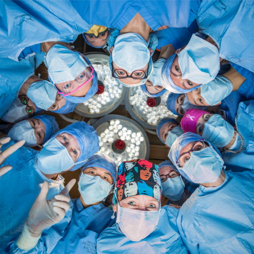 A group of women surgeons look down at the camera in a circle.