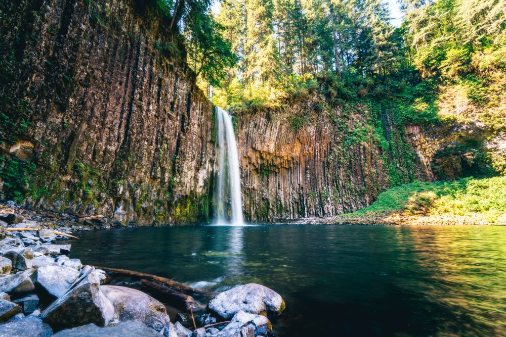 Wide shot of a waterfall pouring over a steep cliff in to a river.