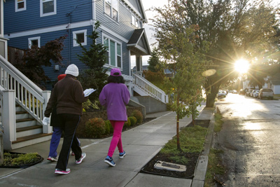 Three women in hats and gloves, walking outdoors together down a neighborhood street