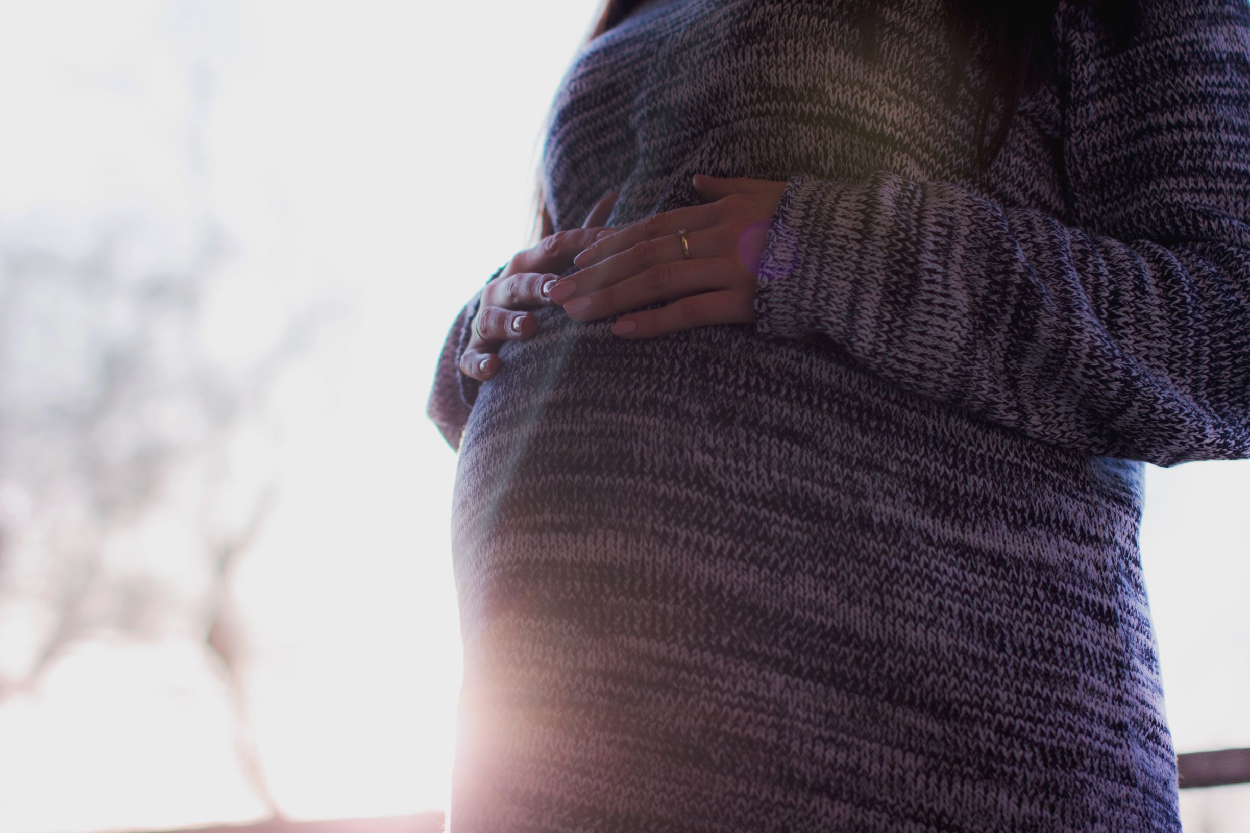 Pregnant woman in sweater touching her stomach