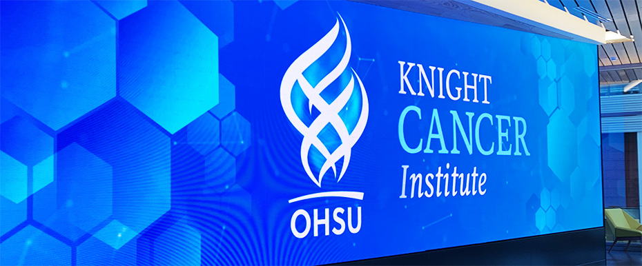 View of the Knight Cancer Institute digital display, a large Knight Cancer Institute logo over a blue technical background