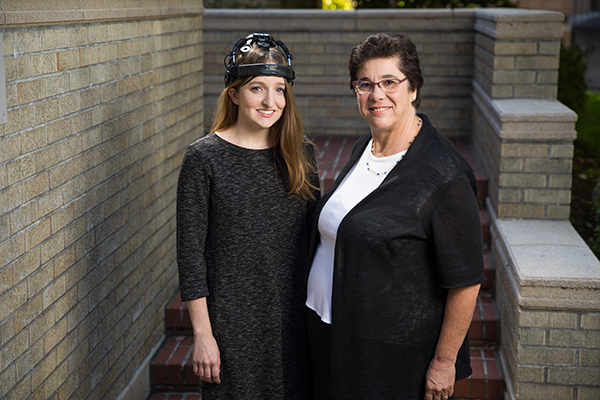 Our research includes developing a system to harness brain signals so people with paralysis can communicate. Research associate Deidre McLaughlin (left) demonstrates the brain-computer interface helmet created by a team led by Melanie Fried-Oken, Ph.D.