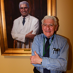 Dr. Frank Parker standing next to his Chairman Portrait Painting