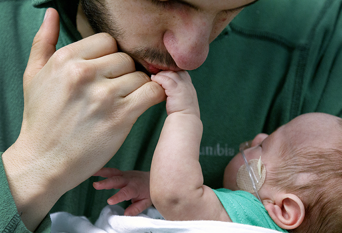 A father kisses his infant's little fingers as the baby is seed by doctors to treat Retinopathy of Prematurity