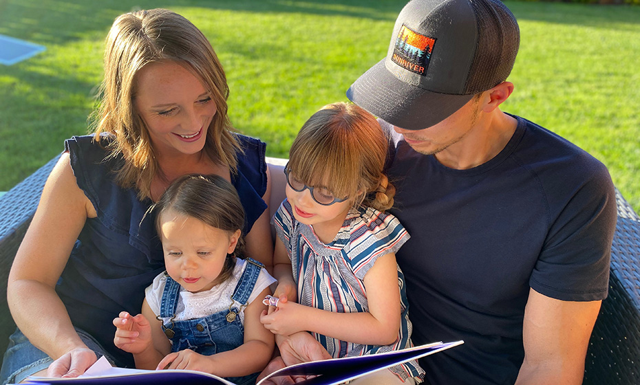 Sienna Balumas and her family reading a book together outside