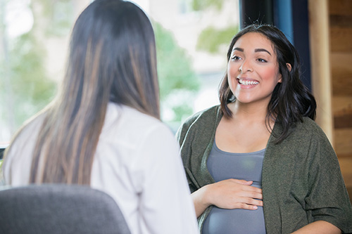 Stock photo of a health care provider talking to a pregnant patient