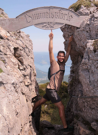 A man pointing up to a sign while on a hike.