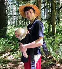 A man carrying a baby while on a hike in the woods.
