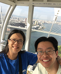A woman and a man smiling while riding the OHSU Tram, with Portland visible in the background.