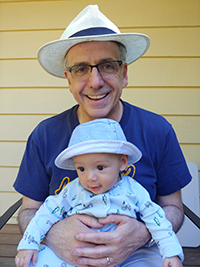 Dr. David Rozansky holding his grandchild smiling.