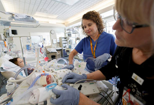 Dr. Cynthia McEvoy and another provider checking on a mother and her newborn baby in their hospital beds.