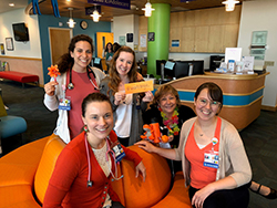 A group of pediatric residents (all women) wearing orange clothing in one of the waiting rooms in Doernbecher Children's Hospital.