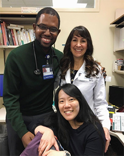 Two pediatric residents (one man and one woman) smiling with Dr. Carrie Phillipi.