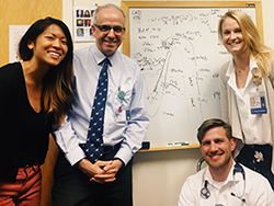 Three pediatric residents (two female and one male) posing in front of a dry-erase board with Dr. David Rozansky.