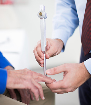 A doctor using a tool on an elderly man's hand that tests sensation.