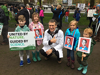 Dr. Jeffrey Jensen crouching down smiling in between 4 kids.