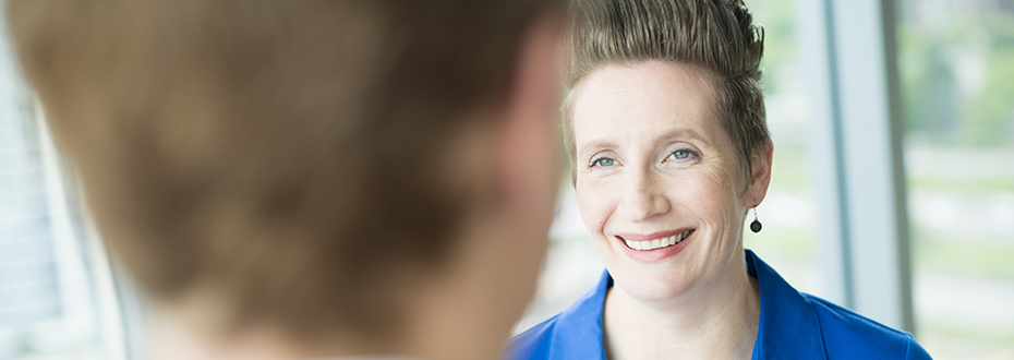 A woman smiling while speaking with her doctor.