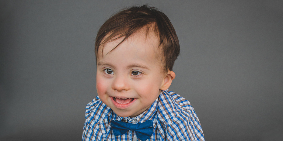 A photo of a little boy wearing a bow tie smiling.