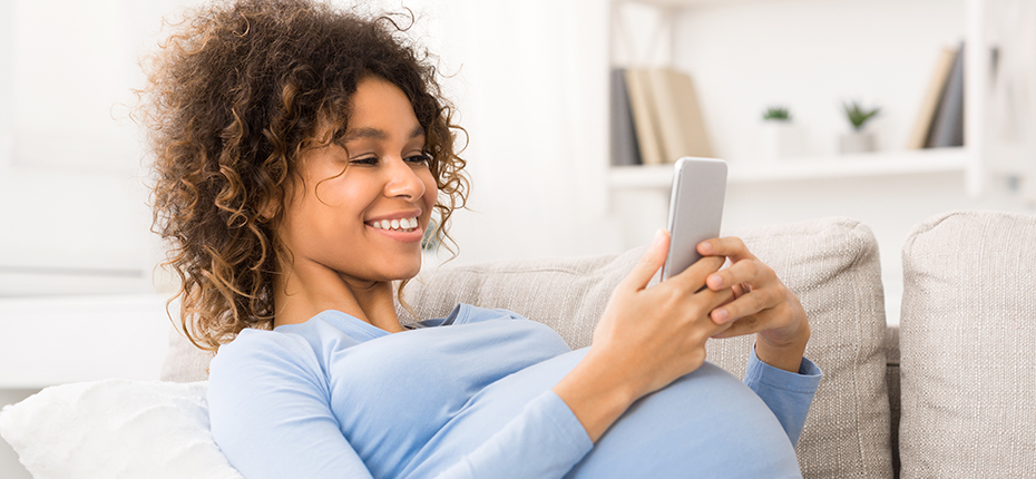 Pregnant woman on couch looking at her phone.