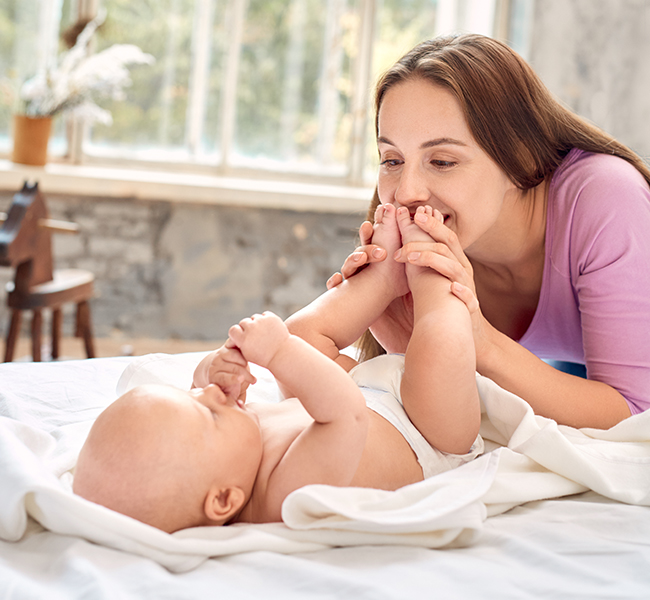 Woman kisses baby's feet.