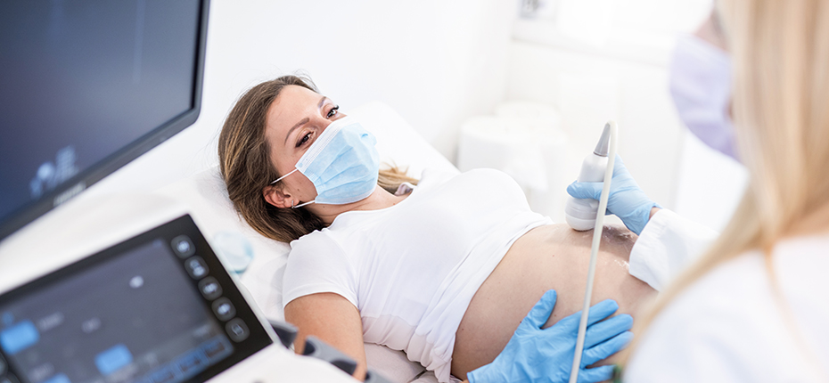 Pregnant woman wearing mask has ultrasound.