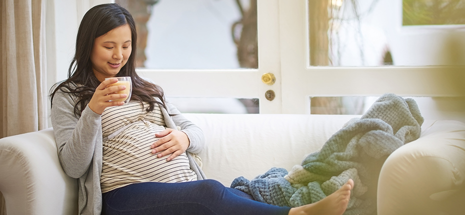 Pregnant woman on couch with cup of tea