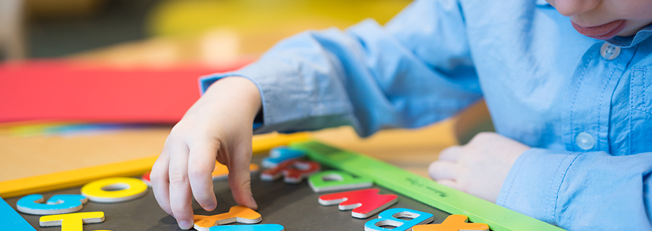 A young boy playing with enlarged alphabet letters.