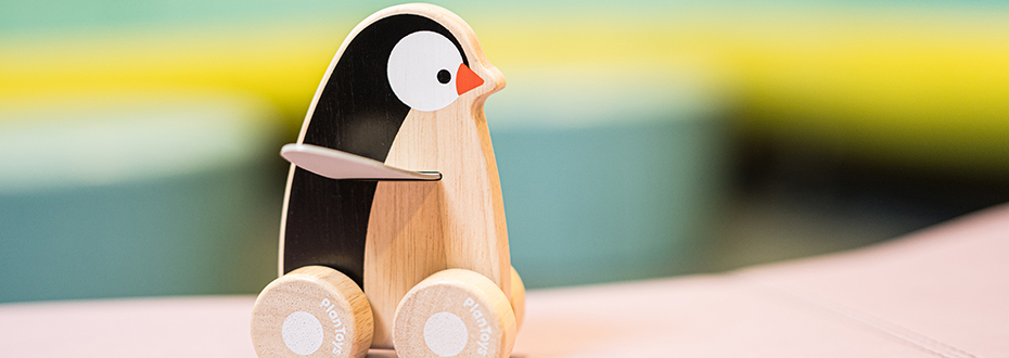 A small wooden toy penguin on wheels.
