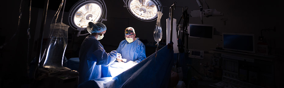 Photo of two surgeons standing in an operating room with large overhead lights