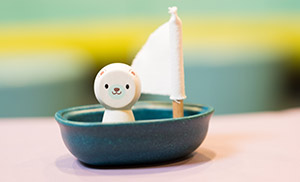 Photo of a toy bear in a small sailboat.