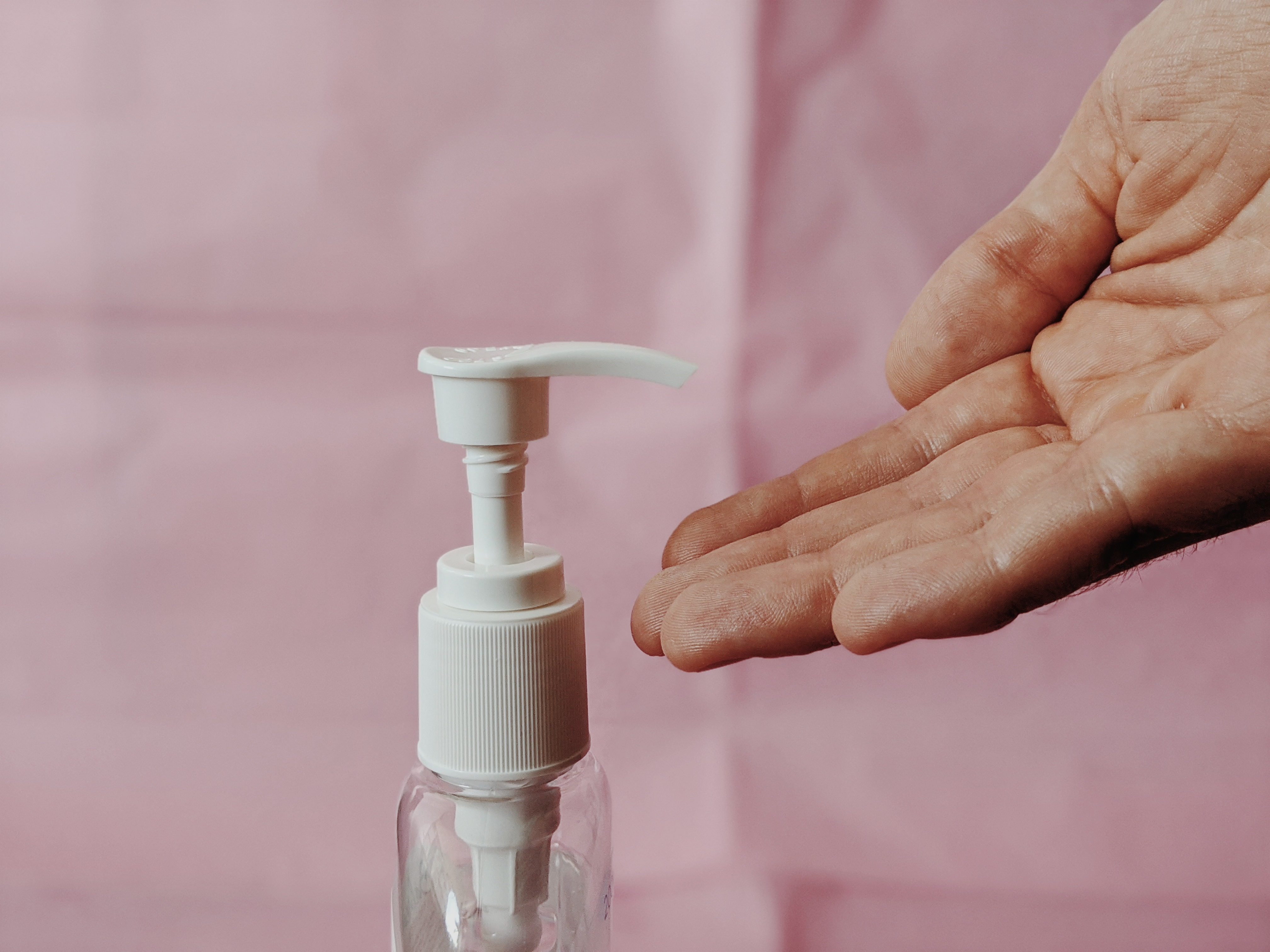Hand sanitizer bottle pictured with a hand ready to clean