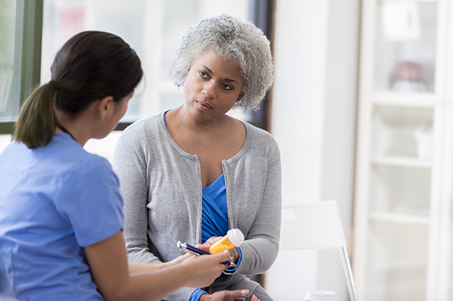 A female health care provider providing instructions as she hands a female patient a new medication.