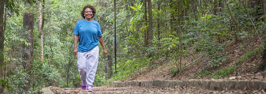A woman smiling while on a hike through a forest.