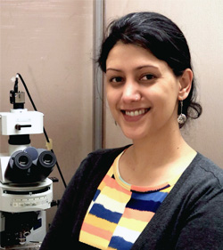 Dr. Anusha Mishra, posed by a microscope