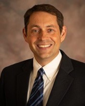 Michael Godsey smiling in a suit and tie