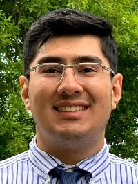 Tony Munoz smiling in a striped button down shirt. 