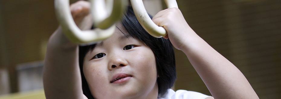 A close up of a young girl holding onto hanging handles.