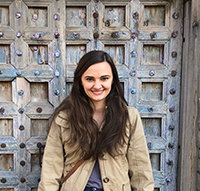 A woman smiling while standing in front of a door.