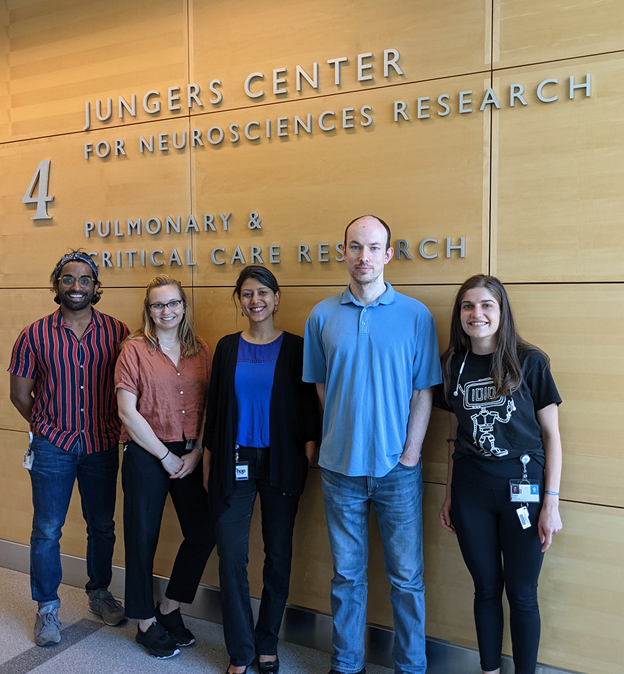 Members of the Mishra Lab smiling, standing in front of the Jungers Center for Neurosciences Research